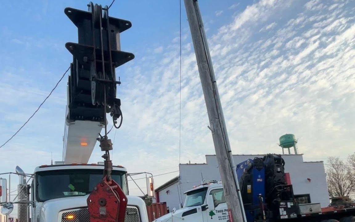 Two boom trucks performing a tandem lift in the street